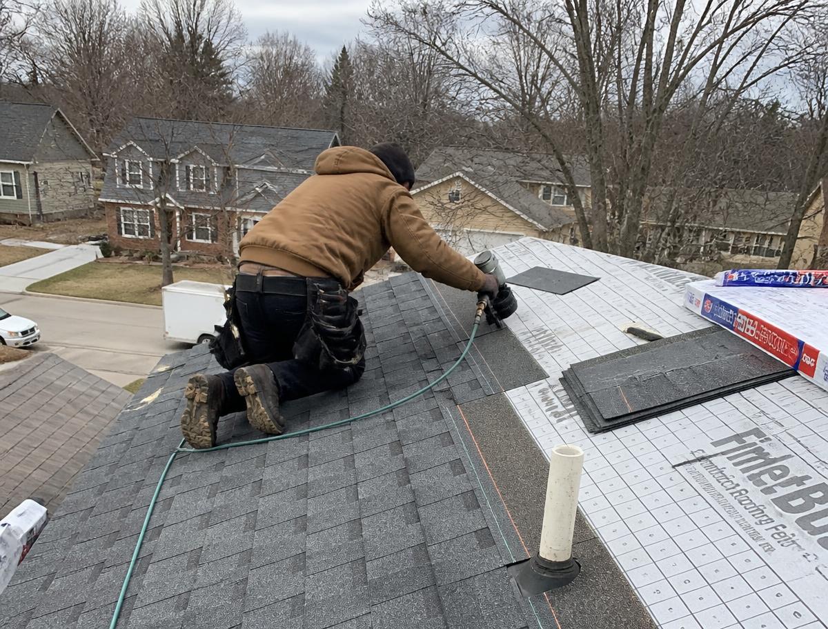 Crew laying architectural shingles on a residential roof